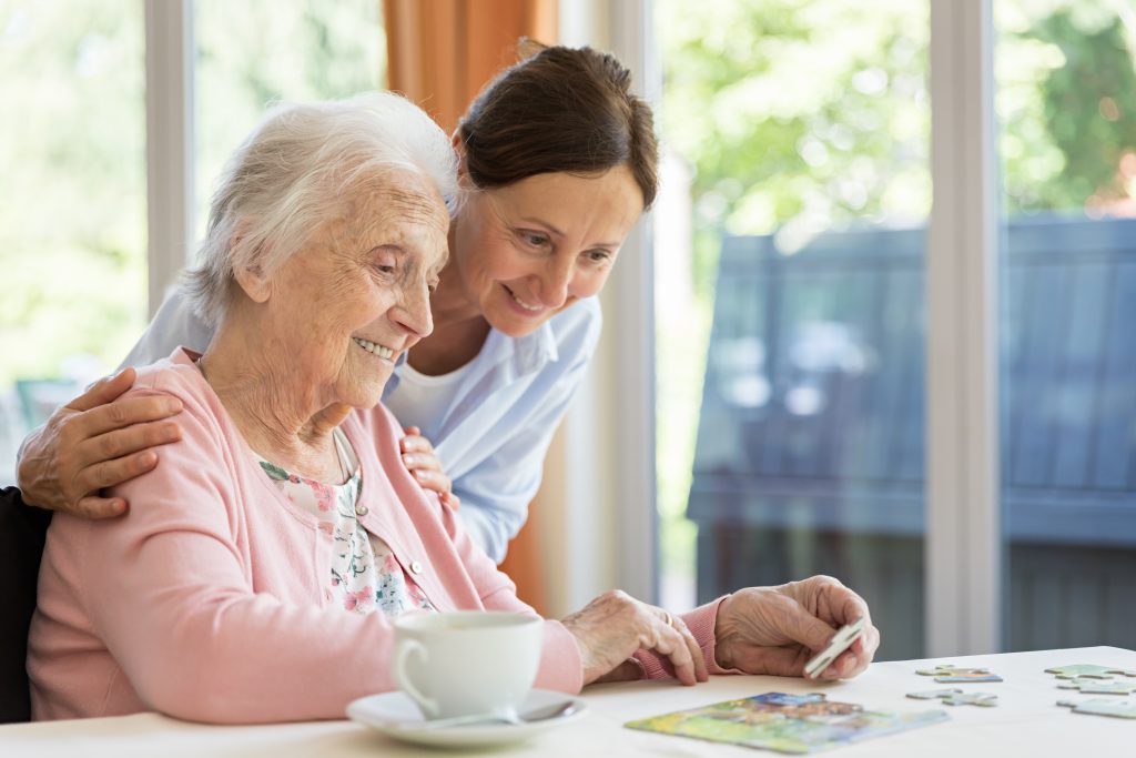 Happy senior woman in wheelchair with caregiver