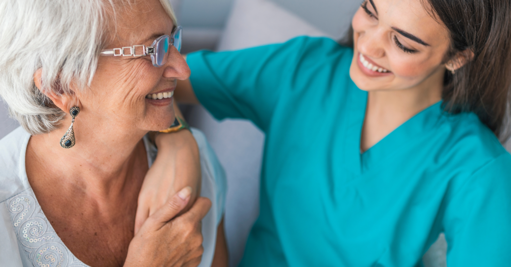 A long-term care resident smiling at a team member wearing blue scrubs