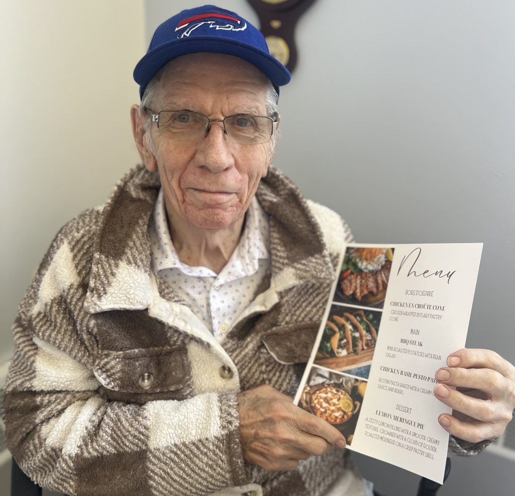 Richard, a resident at Carleton Lodge, holding the menu for a special dinner being served at the home.